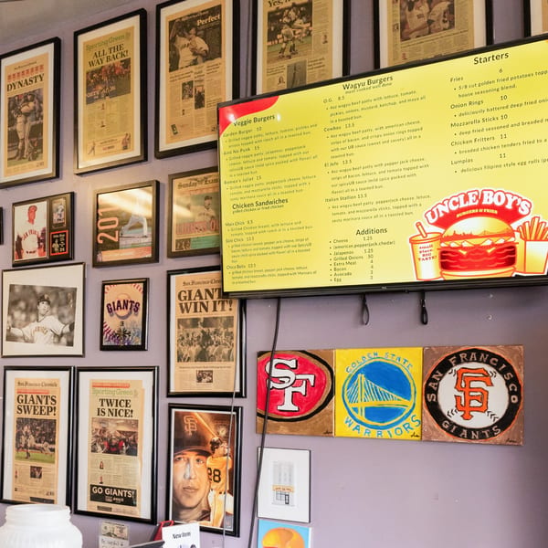 A wall covered with framed newspaper clippings about the San Francisco Giants and a menu for Uncle Boy's burgers.