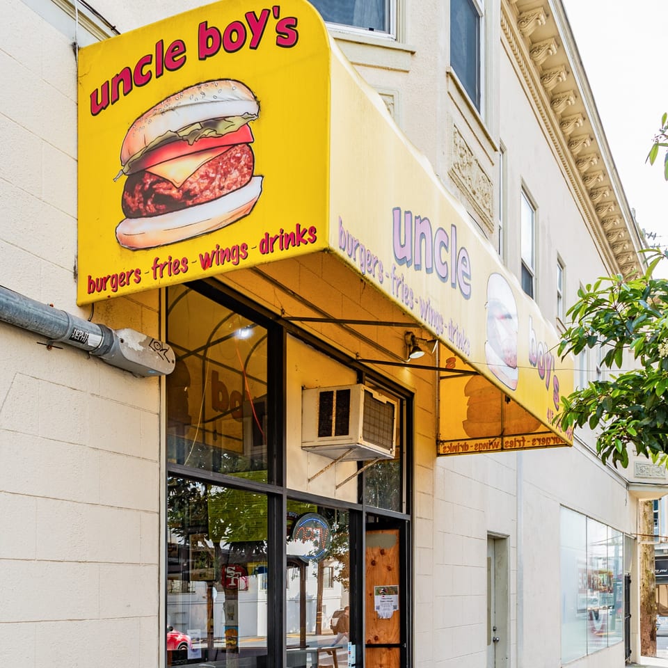 The exterior of Uncle Boy's burger restaurant, featuring a yellow awning with a burger illustration.